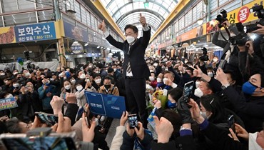 لي جاي-ميونغ (في الوسط) يلوح لمؤيديه خلال حملة انتخابية في سوق في سيجونغ (12 شباط 2022، أ ف ب). 
