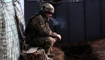 جندي أوكراني يدخن في موقع على خط المواجهة مع الانفصاليين بالقرب من مستوطنة ترويتسكي في منطقة لوغانسك (22 شباط 2022، أ ف ب). 
