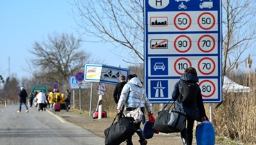 عائلات أوكرانية فارة تمشي على طريق بعد عبور الحدود الهنغارية الأوكرانية بالقرب من بيريغسوراني بهنغاريا (25 شباط 2022، أ ف ب). 