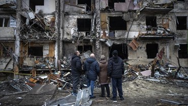 اشخاص وقفوا امام مبنى متضرر في كييف (25 شباط 2022، ا ب). 