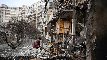 رجل يزيل الركام في مبنى سكني متضرّر في شارع كوشيتسا، إحدى ضواحي العاصمة الأوكرانية كييف (25 شباط 2022 - أ ف ب).