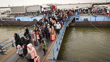 أشخاص آتون من أوكرانيا ينزلون من عبارة لدخول رومانيا بعد عبور نهر الدانوب عند معبر إيزاكيا- أورليفكا الحدودي بين رومانيا وأوكرانيا (26 شباط 2022، أ ف ب). 