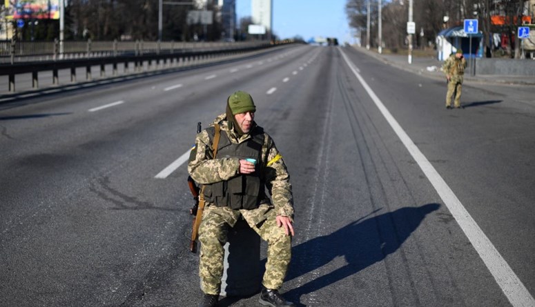 جندي أوكراني يحمل كوبًا من الشاي خلال قيامه بدورية على طريق مقفر على الجانب الغربي من العاصمة الأوكرانية كييف (26 شباط 2022، أ ف ب).