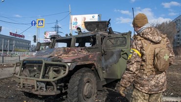 جندي أوكراني يعاين عربة عسكرية روسية مدمرة في مدينة خاركيف أمس (أ ب).