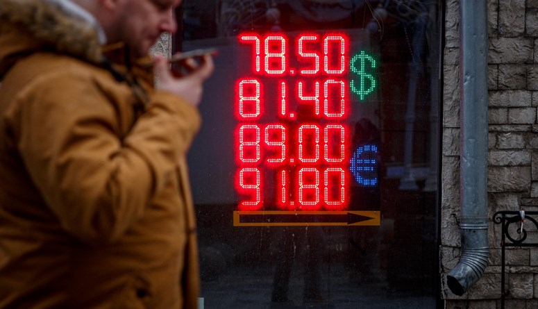 رجل يمرّ بجانب شاشة تعرض أسعار صرف الدولار الأميركيّ واليورو مقابل الروبل الروسي في موسكو (22 شباط 2022 - أ ف ب).