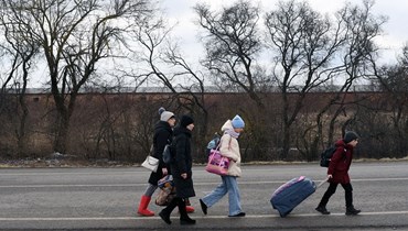 عائلة أوكرانية تمشي باتجاه معبر ميديكا-شاهيني الحدودي بين أوكرانيا وبولندا (أ ف ب).
