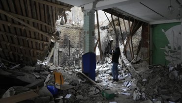 امرأة تلتقط صورًا لمبنى سكني مدمر بالقرب من نقطة تفتيش في بروفاري خارج كييف (1 آذار 2022، أ ب). 