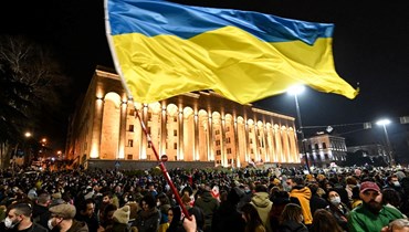 متظاهرون يلوحون بالعلم الأوكراني خلال مسيرة لدعم أوكرانيا في تبليسي (1 آذار 2022، أ ف ب).