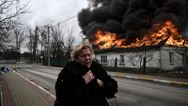 امرأة تمر قرب منزل يحترق بعد تعرضه للقصف في مدينة إيربين خارج كييف (4 آذار 2022، أ ف ب). 