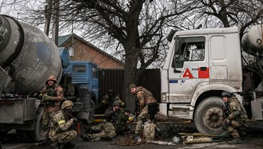 جنود أوكرانيون يحتمون خلال قصف على مدينة بوتشا غرب كييف (4 آذار 2022، ا ف ب). 