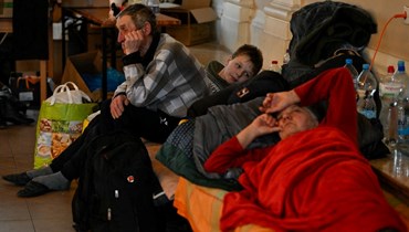 لاجئون من أوكرانيا يستريحون في مأوى موقت في محطة القطارات الرئيسية في كراكوف في بولندا (6 آذار 2022، أ ف ب).  