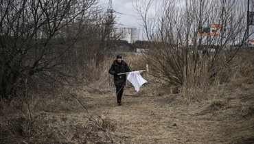 رجل يحمل علماً أبيض بينما يفرّ سكان مدينة إيربين غربي كييف (7 آذار 2022 - أ ف ب).