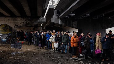 لاجئون أوكرانيون تحت جسر مدمّر أثناء فرارهم من مدينة إيربين، شمال غرب كييف (7 آذار 2022 - أ ف ب).