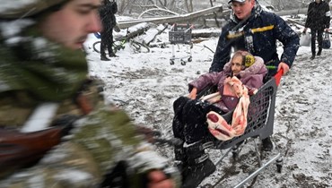 رجل إنقاذ يدفع عربة جلست فيها امرأة عجوز خلال إجلاء المدنيين من مدينة إيربين شمال غرب كييف (8 آذار 2022، أ ف ب). 