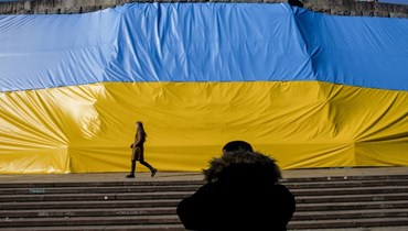 رجل يلتقط صورة لصديقته وهي تمشي أمام علم أوكراني كبير في براغ (أ ف ب). 