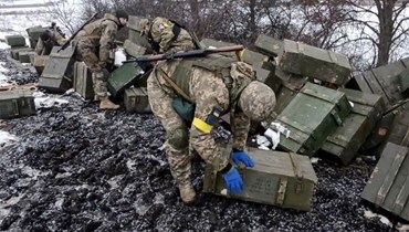 جندي أوكراني يجمع ذخيرة تم الاستيلاء عليها (10 آذار 2022، أ ف ب). 