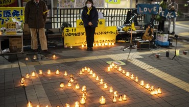اشخاص يشاركون في وقفة بضوء الشموع في ميتاكا في ضواحي طوكيو إحياءً لذكرى ضحايا الزلزال والتسونامي (11 آذار 2022، أ ف ب). 