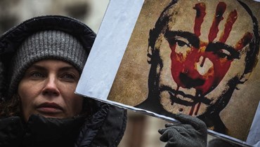 متظاهرة تحمل لافتة تصور بوتين خلال احتجاج في بلغراد ضد الغزو العسكري الروسي لأوكرانيا (6 آذار 2022، ا ف ب). 
