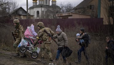جنود أوكرانيون يساعدون عائلة هاربة في عبور نهر إيربين في ضواحي كييف (5 آذار 2022، ا ب). 