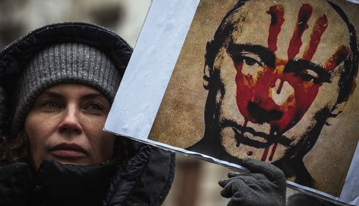 متظاهرة تحمل لافتة تصور بوتين خلال احتجاج في بلغراد ضد الغزو العسكري الروسي لأوكرانيا (6 آذار 2022، أ ف ب).