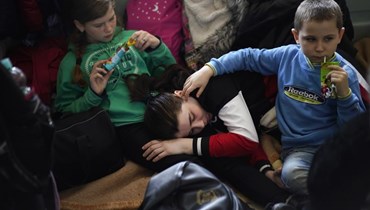 امرأة وطفلان فروا من أوكرانيا، خلال استراحتهم في بهو محطة قطارات في برزيميسل في بولندا (13 آذار 2022، ا ب). 