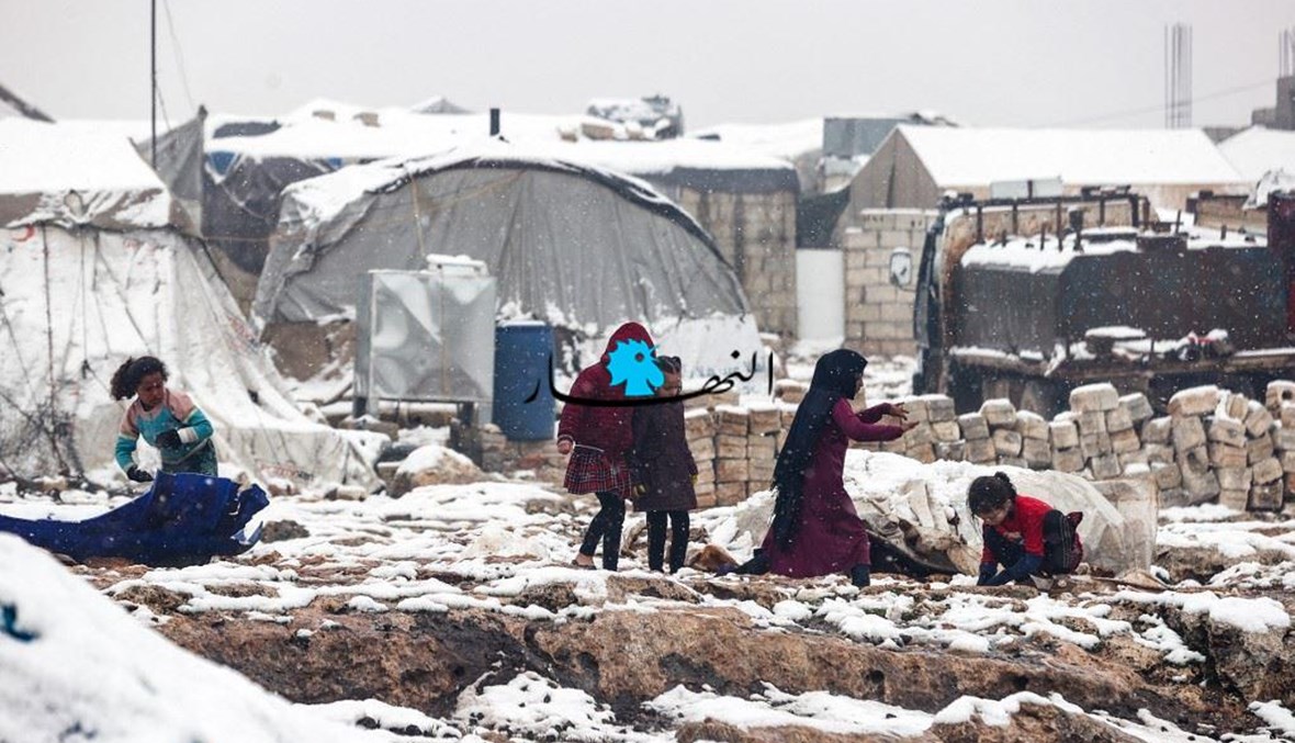 أطفال يلعبون في الثلج في مخيم للنازحين السوريين (أ ف ب).