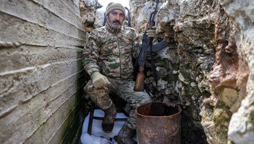 مقاتل من تحالف "الجبهة الوطنية للتحرير"جلس في خندق مغطى بالثلوج في الريف الشمالي الجبلي لمحافظة اللاذقية شمال غرب سوريا (14 آذار 2022، ا ف ب). 