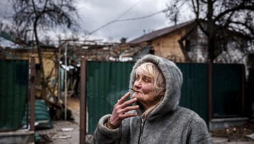فيرا تسيغانوفا، 76 عاماً، تدخّن سيجارة أمام منزلها الذي تضرّر في قصف جوي في مدينة إيربين، شمال غرب كييف (13 آذار 2022 - أ ف ب).