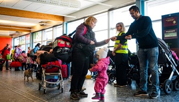 متطوعون يوزعون مواد اعانة ومعلومات على لاجئين أوكرانيين لدى وصولهم الى ميناء نينسهامن جنوب ستوكهولم بالسويد (15 آذار 2022، ا ف ب). 