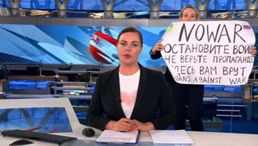 الصحافية مارينا أوفسيانيكوفا ترفع اللافتة الاحتجاجية خلال عرض البرنامج الإخباري في وقت الذروة (أ ف ب).