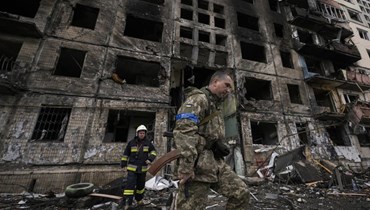 جنود ورجال إطفاء أوكرانيون يفتشون مبنى مدمرًا بعد هجوم تفجيري في كييف (14 آذار 2022، أ ب). 