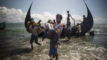 رجل من بنغلاديش يساعد اللاجئين الروهينغا المسلمين على النزول من قارب على الساحل البنغلاديشي لنهر ناف بعد عبور الحدود من ميانمار في تكناف (30 أيلول 2017 - أ ف ب).