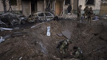 جنود أوكرانيون يعاينون مكان سقوط قذيفة روسية في كييف أمس (أ ب).