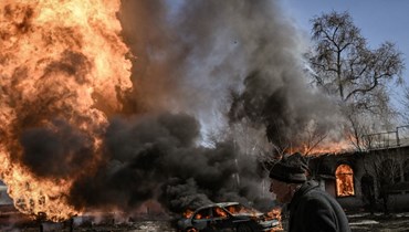 امرأة أوكرانية تمر قرب حريق اندلع من جراء قصف في مدينة خاركيف الشمالية الشرقية (25 آذار 2022، أ ف ب).