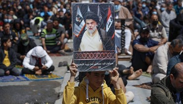 فتى مناصر للتيار الصدري يرفع صورة للزعيم الشيعي العراقي مقتدى الصدر في صلاة الجمعة (أ ف ب).