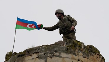 جندي أذربيجاني يرفع العلم الوطني على برج خارج بلدة فضولي (26 تشرين الثاني 2020 - أ ف ب).
