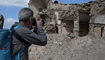 سائح يلتقط صورا للدمار الذي خلفته سنوات من الصراع في مدينة الموصل شمال العراق (12 آذار 2022، أ ف ب). 