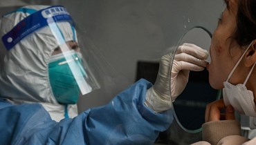 امرأة تخضع لاختبار كشف كورونا بالقرب من مستشفى شنغهاي جينغان المركزي في شنغهاي (26 آذار 2022، ا ف ب). 