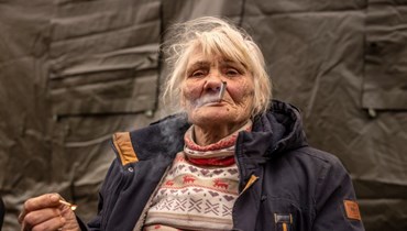 امرأة تدخن سيجارة بعد الفرار من منزلها في ضواحي كييف (أ ف ب). 