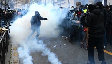 متظاهرون وسط الغاز المسيل للدموع في باريس (5 ك1 2020، أ ف ب).