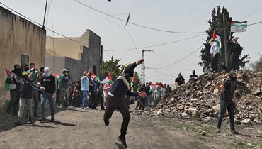 فلسطينيون خلال اشتباكات مع قوات الأمن الإسرائيلية في قرية كفر قدوم بالقرب من مستوطنة كدوميم في الضفة الغربية المحتلة (1 نيسان 2022، أ ف ب).  