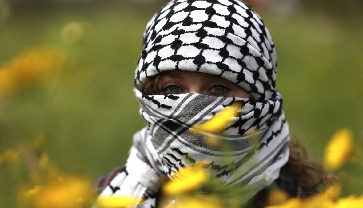 فتاة تغطّي وجهها بالوشاح الفلسطيني (أ ف ب).