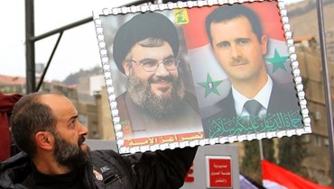 رجل يرفع صورة للأسد ونصرالله (أرشيف "أ ف ب").