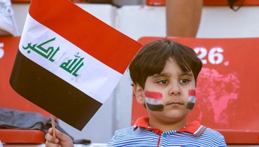 مشجع صغير للعراق يلوح بالعلم في المدرجات في ملعب راشد في إمارة دبي، قبيل مباراة بين العراق وسوريا في تصفيات كأس العالم لكرة القدم قطر 2022 (29 آذار 2022، أ ف ب). 