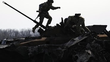 جندي أوكراني تسلق مركبة قتالية روسية مدمرة في بوتشا بأوكرانيا (7 نيسان 2022، أ ب). 