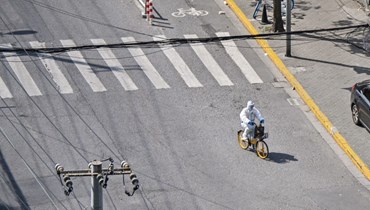 عامل يركب دراجة في أحد الشوارع في شنغهاي خلال الاغلاق (8 نيسان 2022، أ ف ب). 