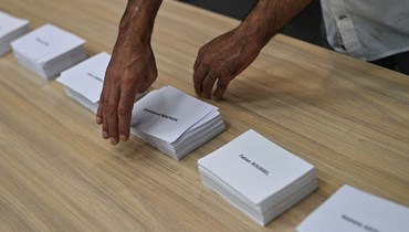 مسؤول بالسفارة الفرنسية يرتبّ أوراق اقتراع تحمل أسماء مرشحي الرئاسة الفرنسية للناخبين للإدلاء بها في الجولة الأولى من الانتخابات في السفارة الفرنسية في بانكوك في 10 نيسان 2022 (أ ف ب).