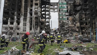 عمال طوارئ تجمعوا امام مبنى مدمّر في بورودينكا بأوكرانيا (9 نيسان 2022، أ ب).
