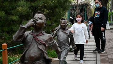 أشخاص يمرون قرب منحوتات في حديقة في بيجينغ (9 نيسان 2022، أ ف ب). 