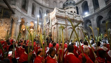 كهنة كاثوليك يحملون أغصان النخيل في كنيسة القيامة في القدس خلال أحد الشعانين (10 نيسان 2022، أ ف ب). 